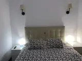 Straight-on view of the beige padded headboard and heart-pattern duvet of the double bed in the interior apartment